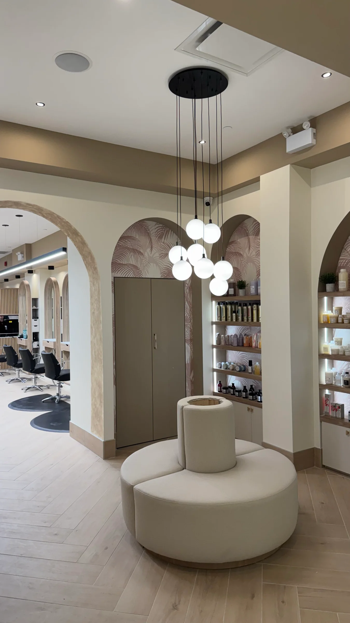 Round upholstered bench and globe pendant lights at the salon entrance
