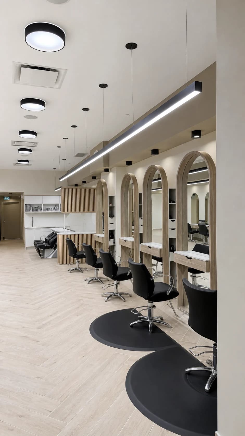 Row of styling chairs and illuminated arched mirrors along the salon floor