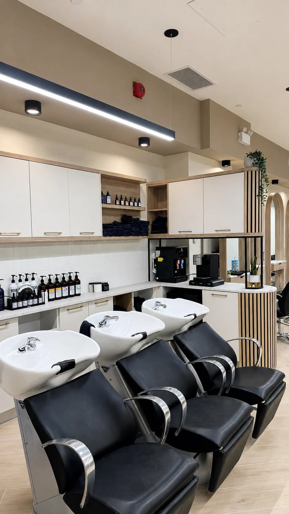 Shampoo area with white washbasins and black reclining chairs at Salon Capelli