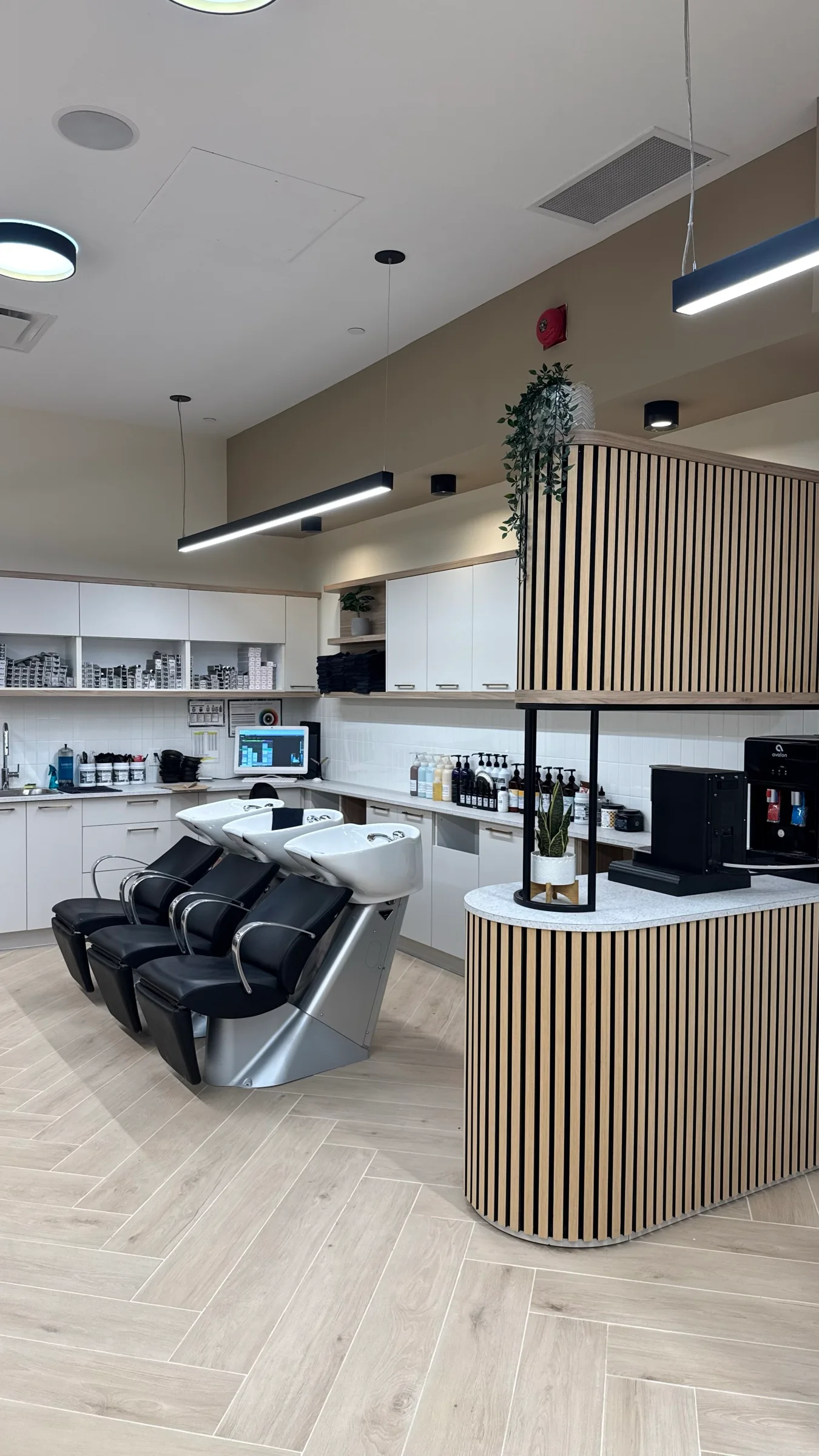 Shampoo lounge and curved wood-detailed counter at the back of the salon
