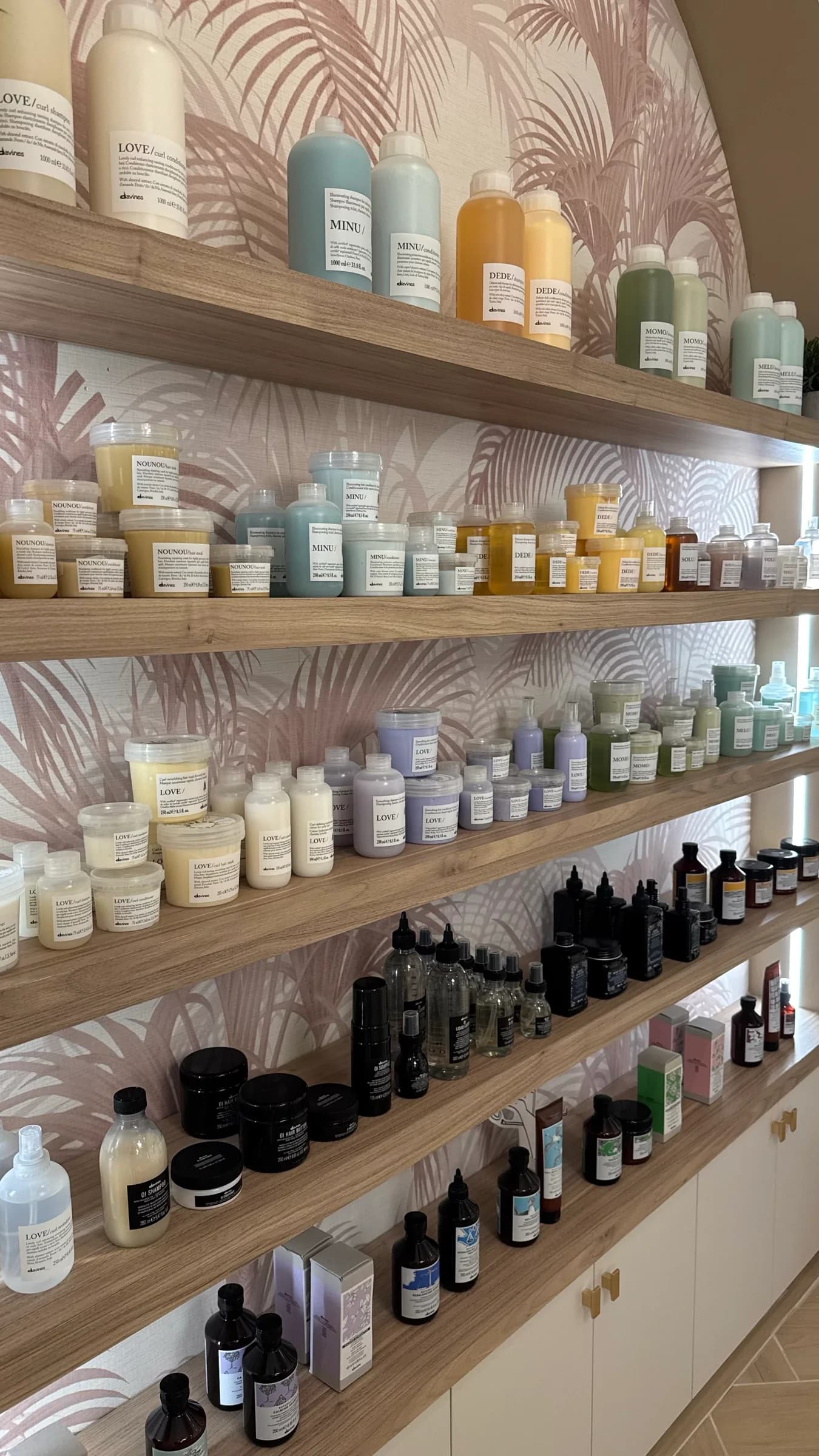 Salon haircare products arranged on wood shelves against a patterned display wall